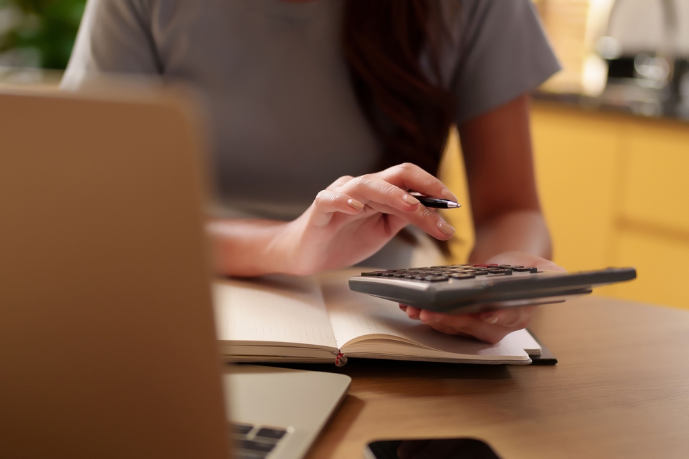 หญิงสาวกดเครื่องคิดเลขคำนวณค่าธรรมเนียมกู้ธนาคารซื้อคอนโด