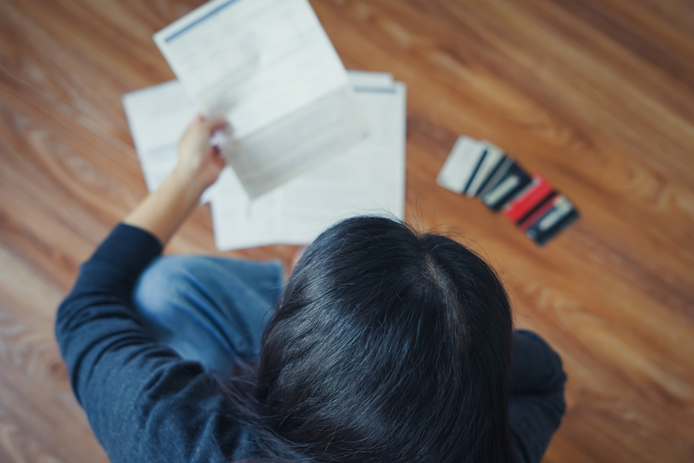 หญิงสาวตรวจเอกสารแสดงยอดหนี้ค้างชำระที่ทำให้ติดแบล็คลิสต์